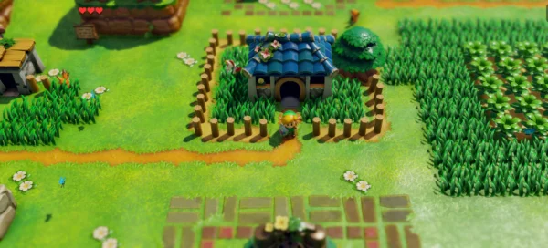 Link stands outside a blue-roofed house in the bright, toy-like world of Link’s Awakening.