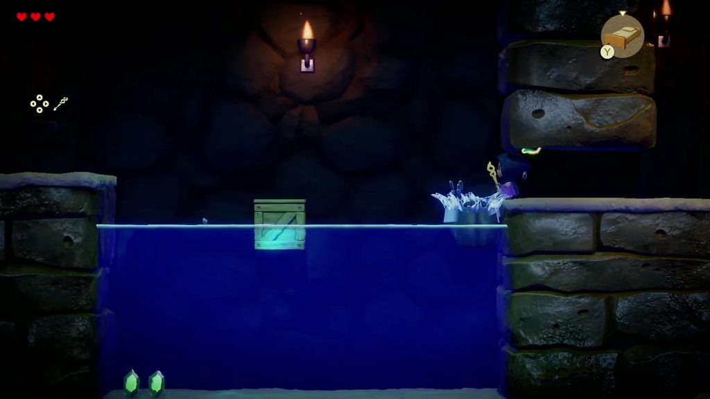 Zelda shoves the loose boulder off the ledge so it splashes into the underground waterway
