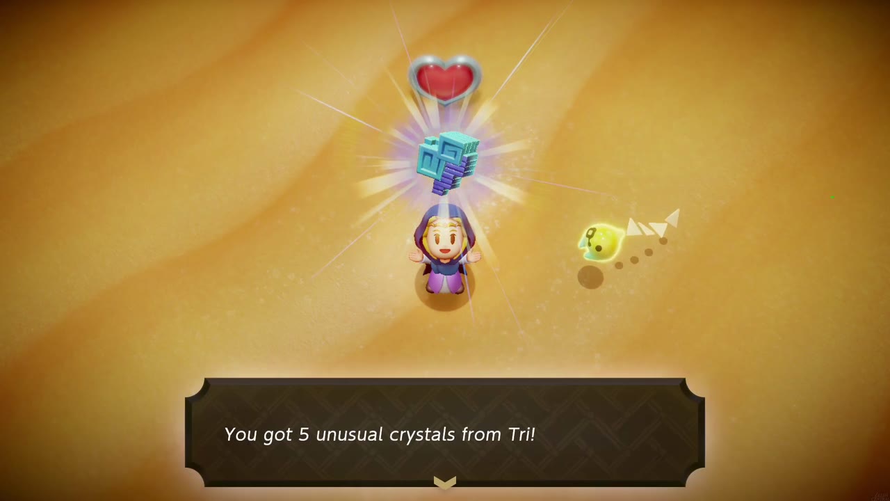 Zelda holds up 5 unusual crystals from Tri on the sand of the Gerudo Sanctum boss arena, a heart container above her