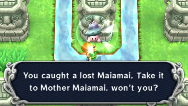 Link catching a lost Maiamai on a stone statue ringed by shallow water, with the catch message on screen
