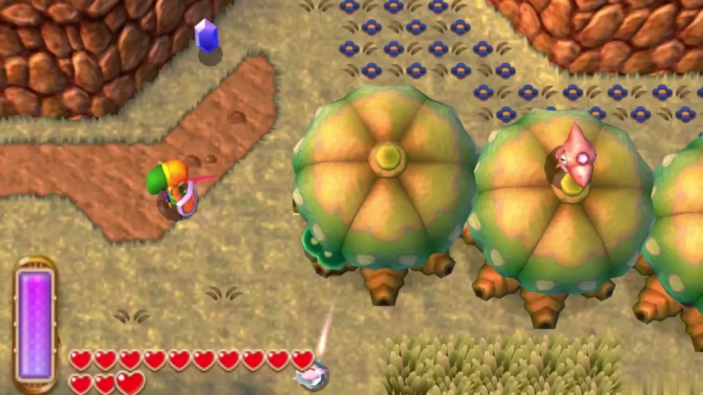 Link beside a row of round trees on Lorule's tan ground, a lost Maiamai perched on top of the second tree Link beside a row of round trees on Lorule's tan ground, a lost Maiamai perched on top of the second tree