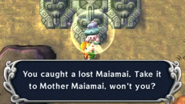 Link holding up a lost Maiamai in a bubble in front of the three stone statues, with the catch message complete
