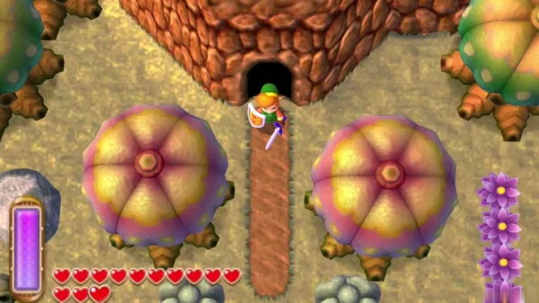 Link at a dark cave entrance on a sandy path, with a large grey rock at the left edge
