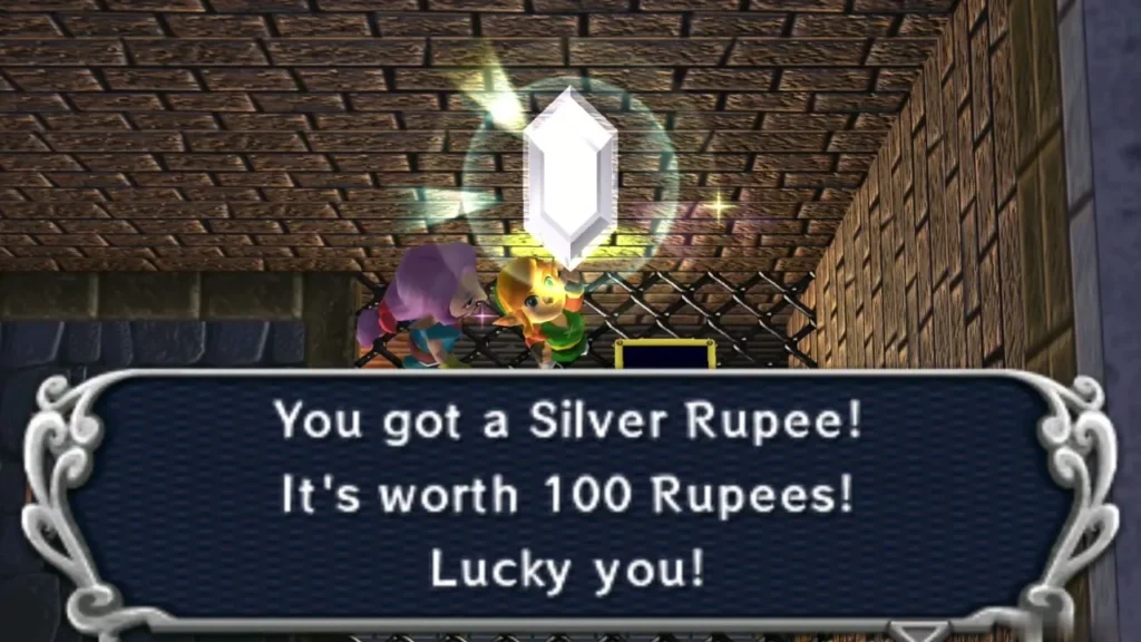 Link holding up a Silver Rupee with the message that it is worth 100 Rupees Link holding up a Silver Rupee with the message that it is worth 100 Rupees