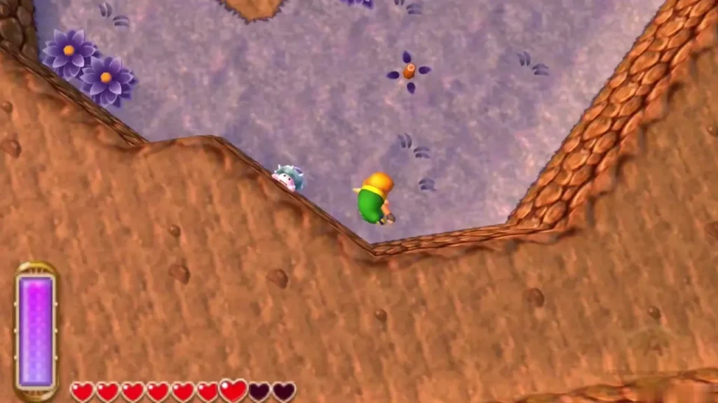 A Lost Maiamai sits on open ground below the rocky ledge as Link walks toward it