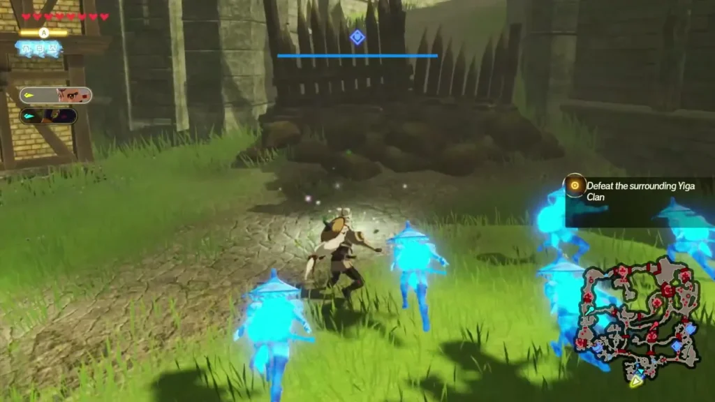 Link battles beside a wooden fence and rock pile at the village edge, with the Defeat the surrounding Yiga Clan objective Link battles beside a wooden fence and rock pile at the village edge, with the Defeat the surrounding Yiga Clan objective