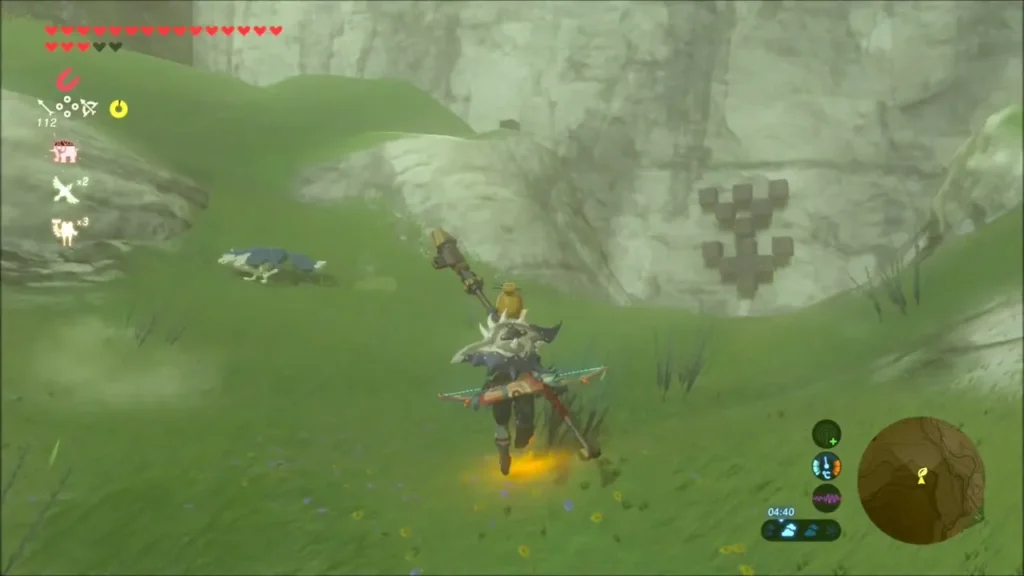 Link running through the grass toward a column of stone blocks on a rock face Link running through the grass toward a column of stone blocks on a rock face