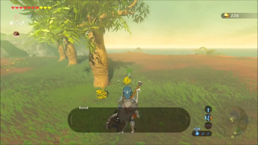 Link in the grass with the Korok and a flower beside the tree