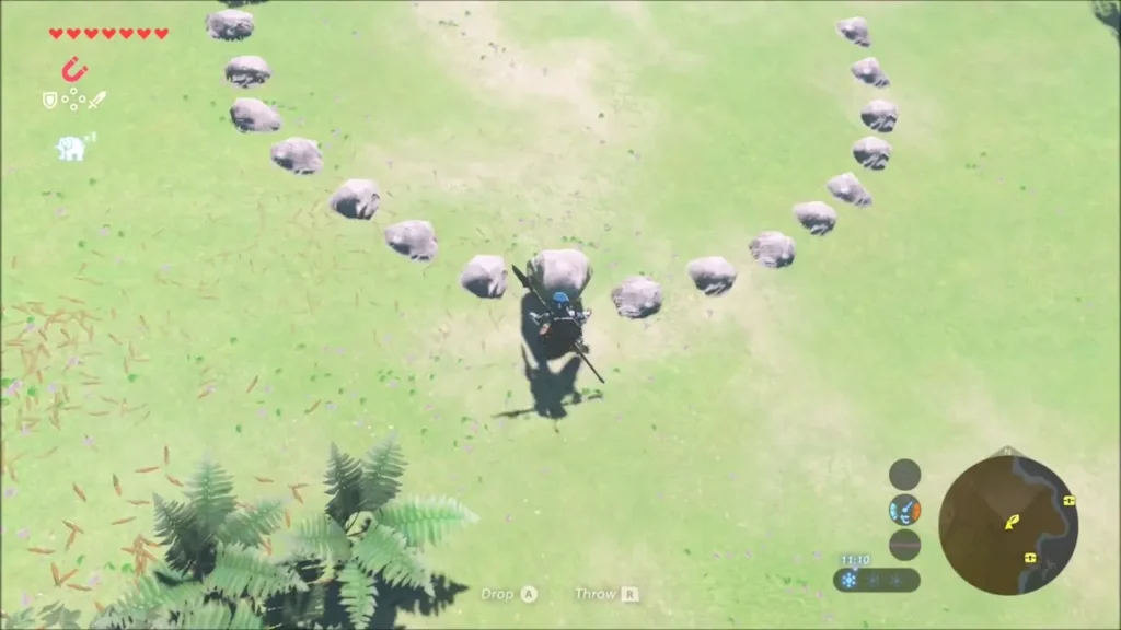 Link approaching a large ring of small stones on a green hillside