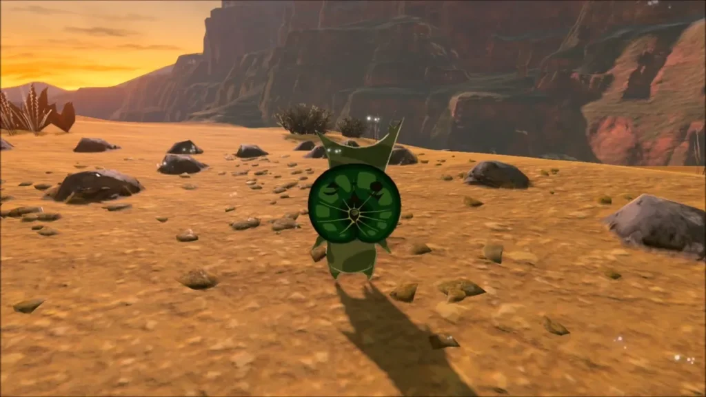 A round green Korok standing among scattered stones on the desert floor A round green Korok standing among scattered stones on the desert floor