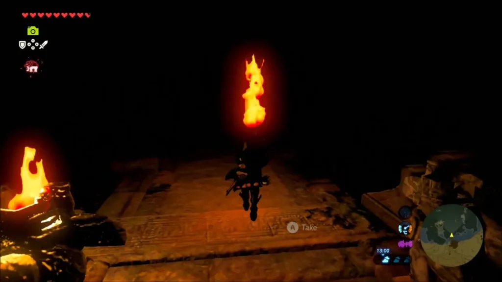 Link carrying a lit torch past a burning statue in the ruins
