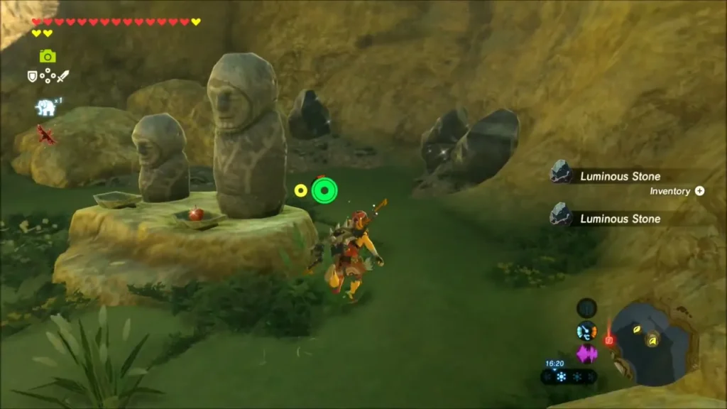 Two small stone statues on a slab with an apple at one foot Two small stone statues on a slab with an apple at one foot