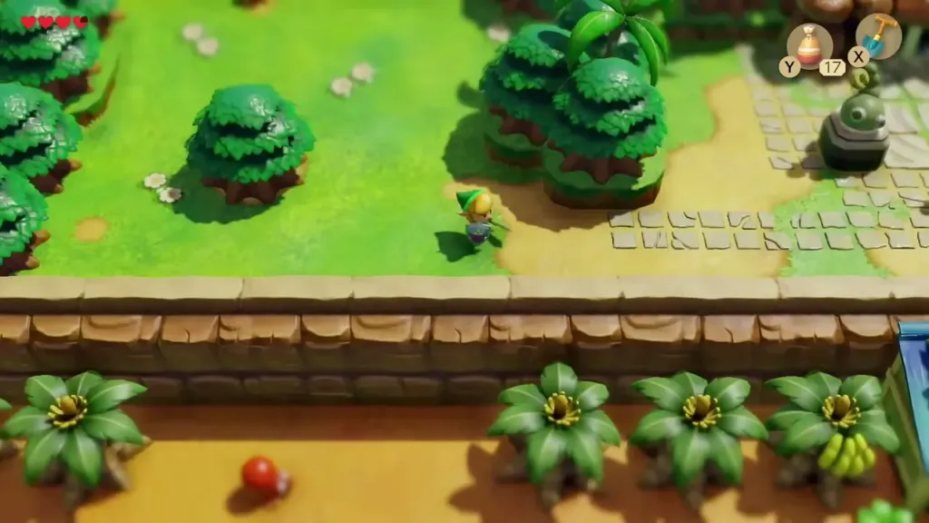 Link walking a grassy path toward Tail Cave past palm trees and a snake statue Link walking a grassy path toward Tail Cave past palm trees and a snake statue