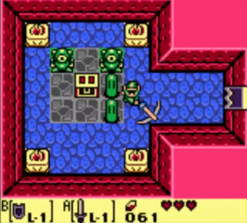 Link swings the Sword at a green Zol beside a grey-tiled block in the blue-floored Tail Cave room Link swings the Sword at a green Zol beside a grey-tiled block in the blue-floored Tail Cave room