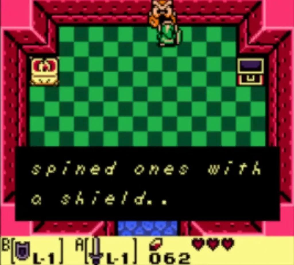 An owl statue's hint reads spined ones with a shield as Link stands before it in Tail Cave An owl statue's hint reads spined ones with a shield as Link stands before it in Tail Cave