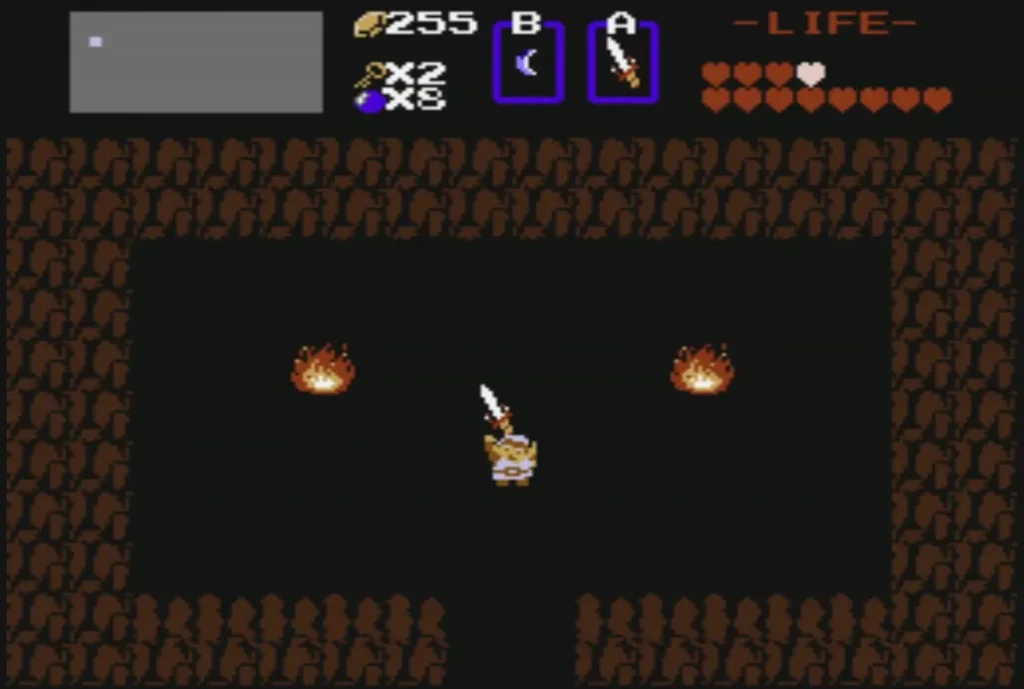 Link holding the Magical Sword overhead in the cave with fires Link holding the Magical Sword overhead in the cave with fires