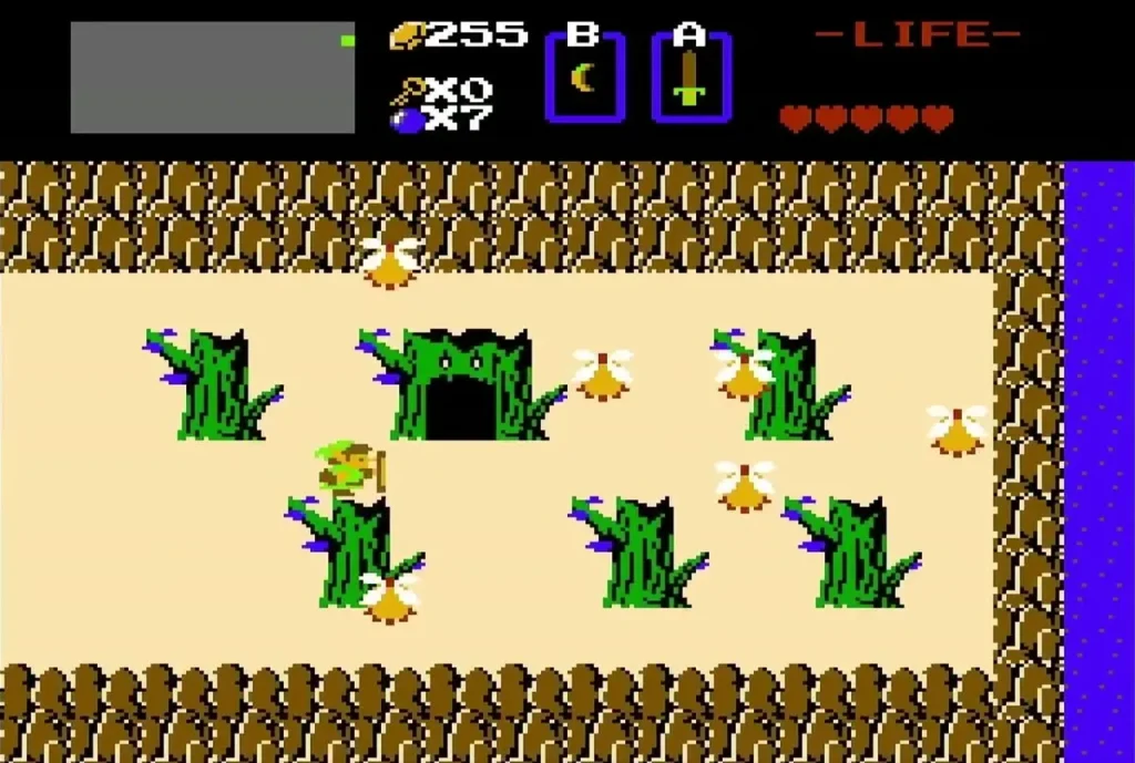 Link on the sand beside a field of three green statues with a dark cave opening in the middle Link on the sand beside a field of three green statues with a dark cave opening in the middle
