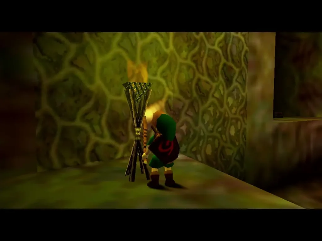 Link at a lit torch in the Deku Tree holding a Deku Stick Link at a lit torch in the Deku Tree holding a Deku Stick