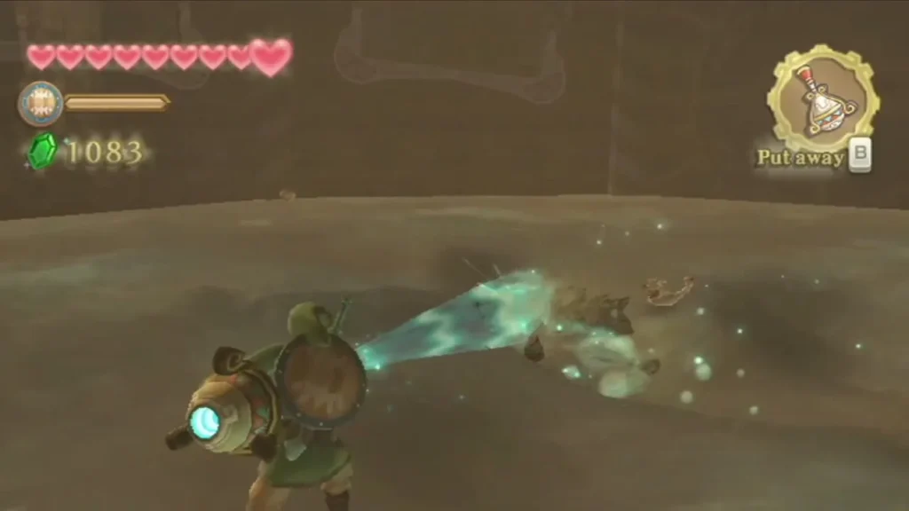 Link blasts sand with the Gust Bellows in the arena, the wind scattering dust and debris across the floor. Link blasts sand with the Gust Bellows in the arena, the wind scattering dust and debris across the floor.