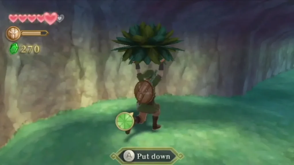Link holds a leafy Kikwi disguised as a plant over his head, with a Put down prompt on screen. Link holds a leafy Kikwi disguised as a plant over his head, with a Put down prompt on screen.