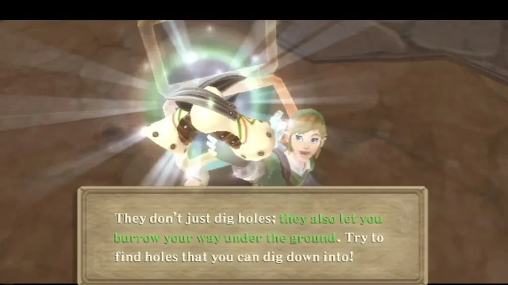 Link holds up the Mogma Mitts, and the box says they let him burrow under the ground. Link holds up the Mogma Mitts, and the box says they let him burrow under the ground.