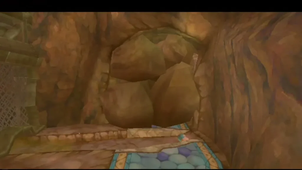 A heap of boulders fills a narrow stone passage with a blue-tiled floor in front of it.