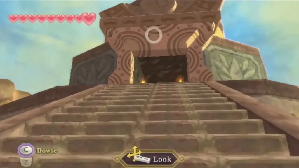 Stone stairs climb to the dark doorway of the Lanayru Mining Facility, with a Look prompt on screen. Stone stairs climb to the dark doorway of the Lanayru Mining Facility, with a Look prompt on screen.