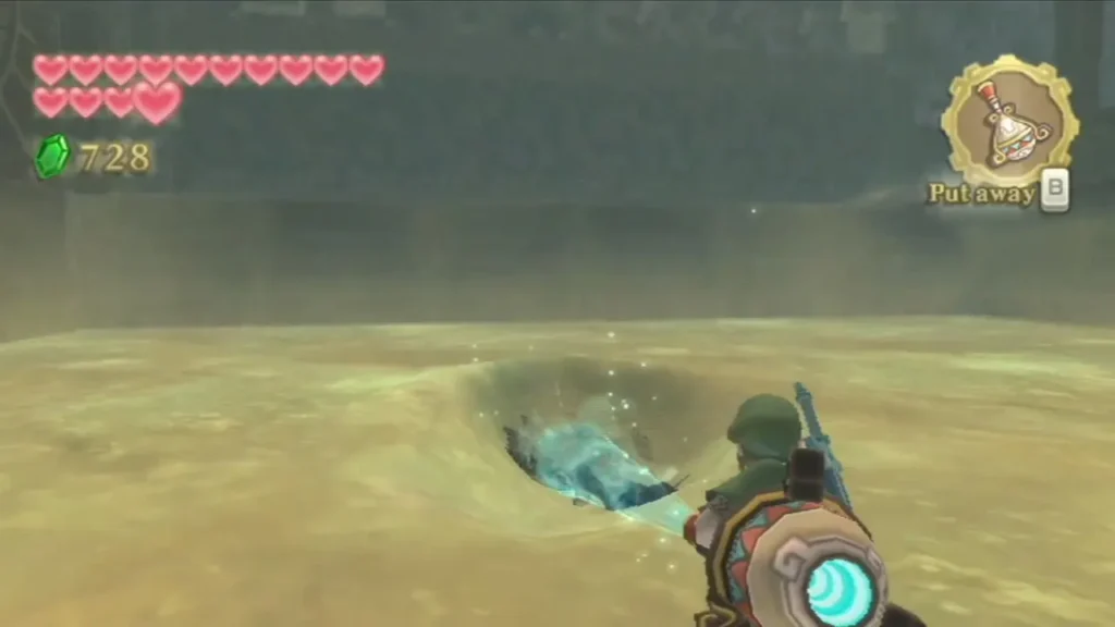 Link uses the Gust Bellows to blow sand out of a hole in the arena floor. Link uses the Gust Bellows to blow sand out of a hole in the arena floor.