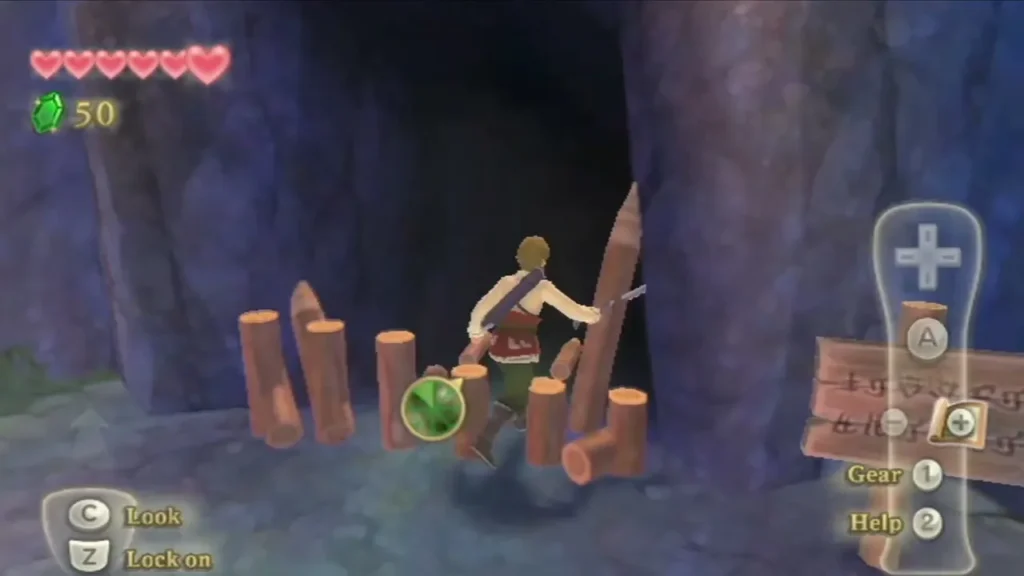 Link walks through a line of wooden stakes toward the dark entrance of the cave in the cliffs. Link walks through a line of wooden stakes toward the dark entrance of the cave in the cliffs.