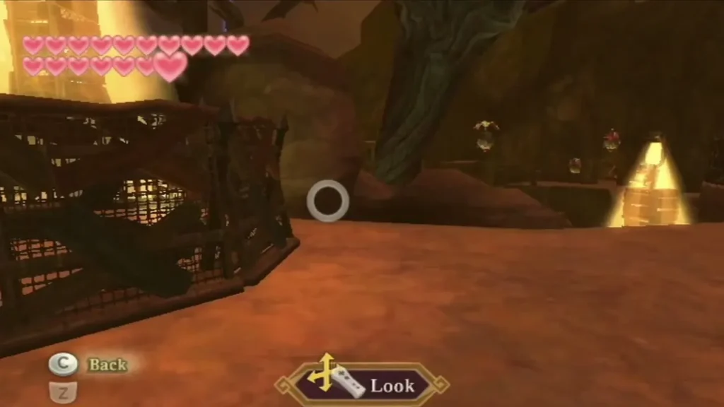 Link peers through a wire fence along a cave path toward distant lanterns and a bright light.
