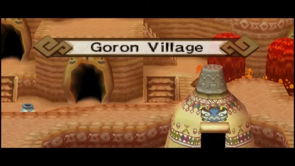 The Goron Village name banner over a carved sandstone street with cave doorways and a Goron statue