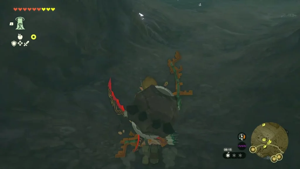 Dark cave opening in the cliff below the snowy ledge