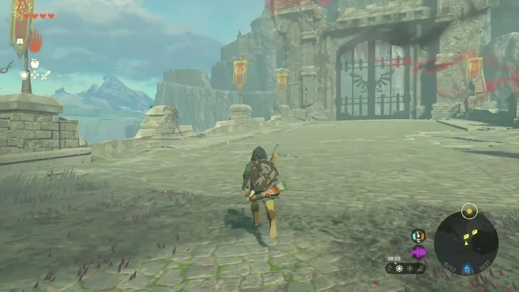 Hyrule Castle's closed main gate with red banners seen from the grass below the ruins Hyrule Castle's closed main gate with red banners seen from the grass below the ruins