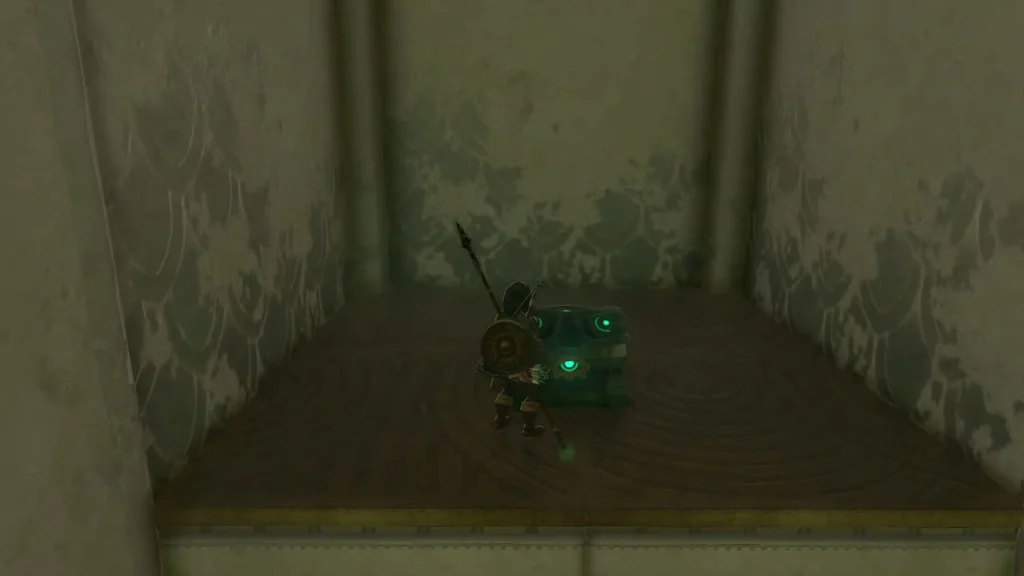Chest on the floor of a small dim room at the top of the ledge