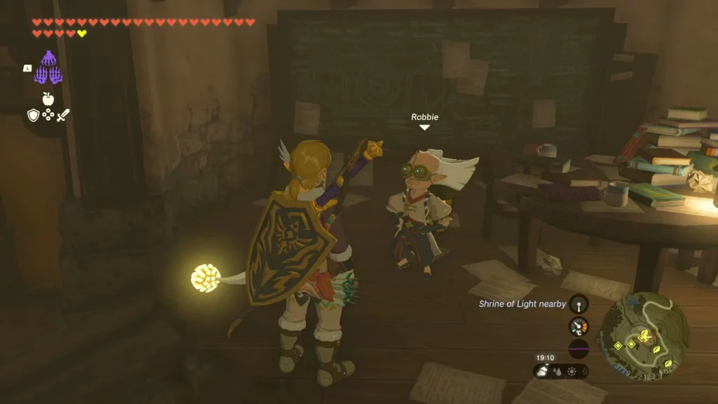 Robbie inside the cluttered Hateno Ancient Tech Lab with a shrine nearby alert