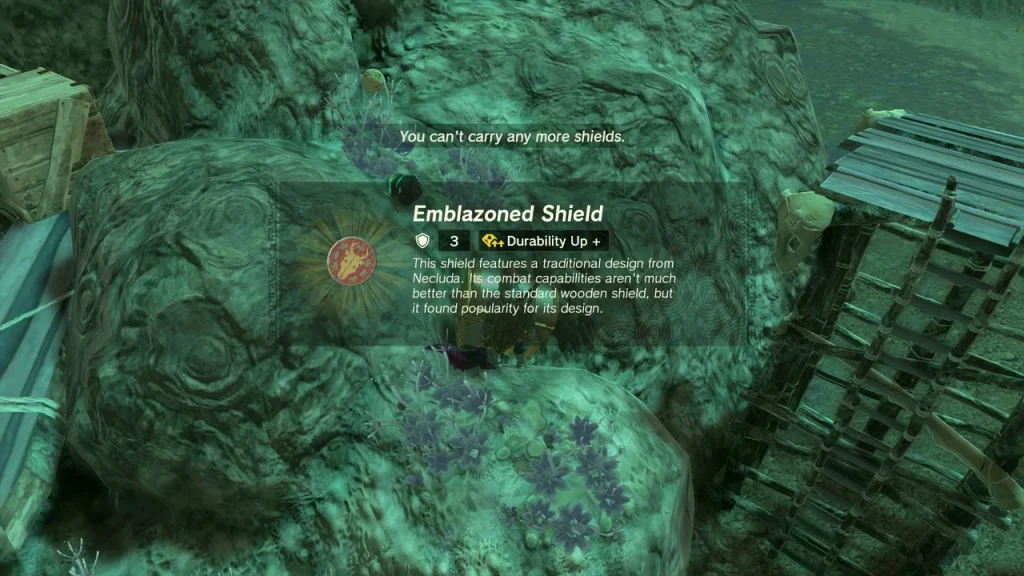 Emblazoned Shield item box on a rocky ledge beside wooden scaffolding Emblazoned Shield item box on a rocky ledge beside wooden scaffolding