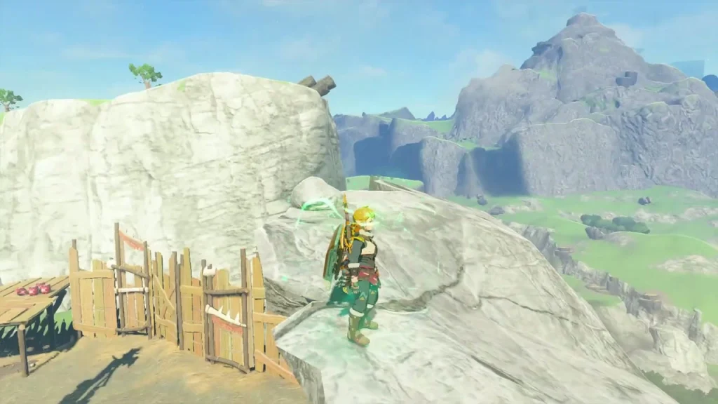White rock ledge above the camp fence with a mountain behind it, hiding a Korok under the stone White rock ledge above the camp fence with a mountain behind it, hiding a Korok under the stone